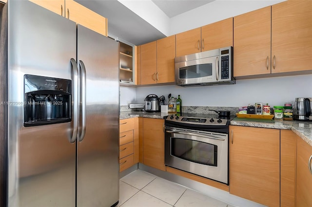 kitchen with light stone countertops, appliances with stainless steel finishes, and light tile patterned floors