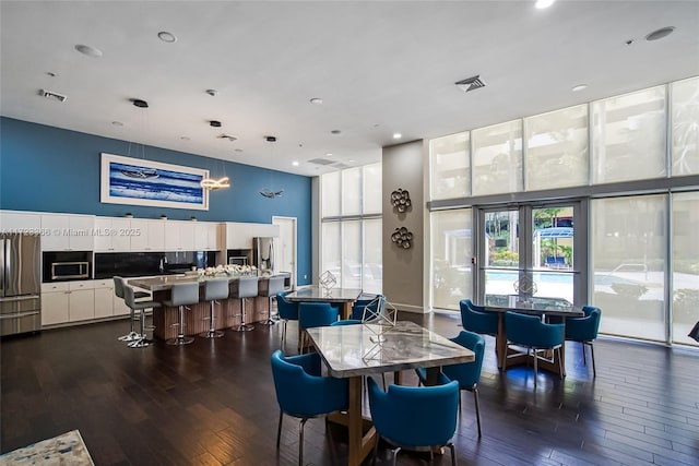 dining space featuring expansive windows, dark wood-type flooring, and a high ceiling