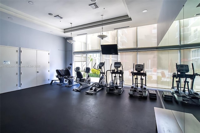 gym with a raised ceiling, floor to ceiling windows, and a towering ceiling