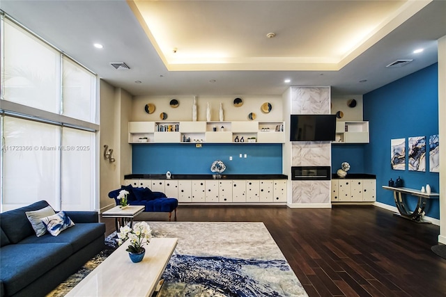 living room with a tray ceiling and dark hardwood / wood-style floors