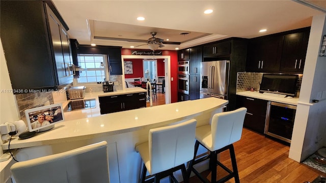 kitchen featuring a kitchen bar, appliances with stainless steel finishes, kitchen peninsula, and a raised ceiling