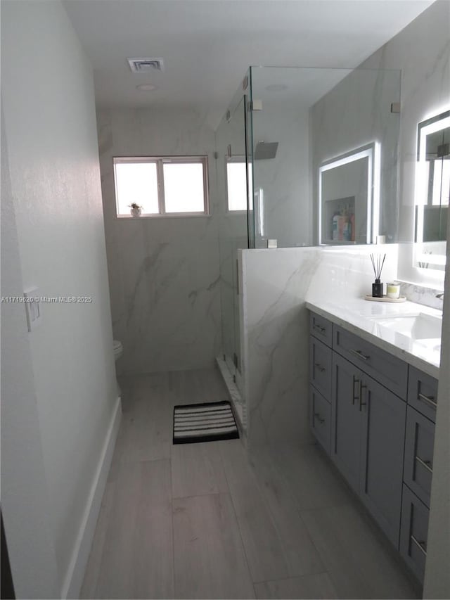 bathroom with vanity, toilet, and a shower with door