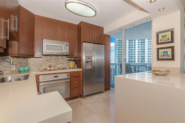 kitchen with backsplash, floor to ceiling windows, sink, light tile patterned flooring, and appliances with stainless steel finishes