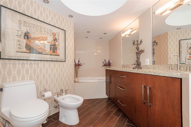 bathroom with a tub to relax in, vanity, a bidet, and toilet