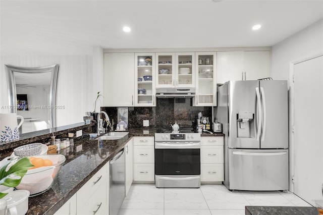 kitchen with decorative backsplash, appliances with stainless steel finishes, sink, dark stone countertops, and white cabinetry