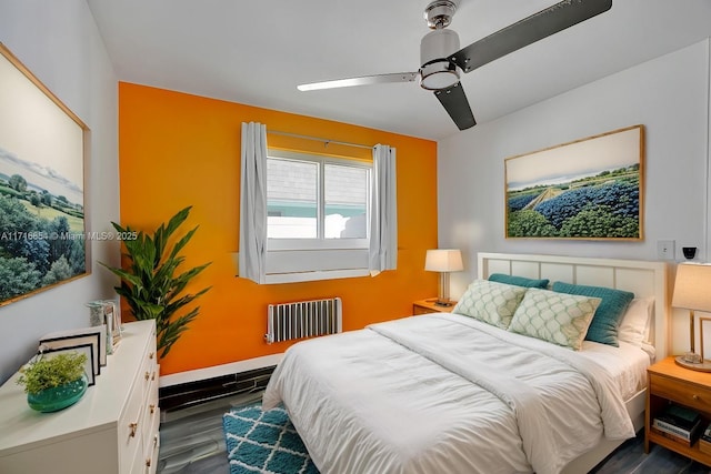 bedroom featuring dark hardwood / wood-style flooring, ceiling fan, and radiator heating unit