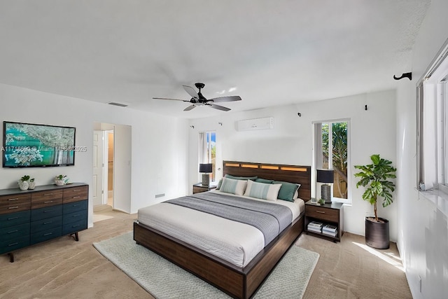 bedroom with ceiling fan, an AC wall unit, and light carpet