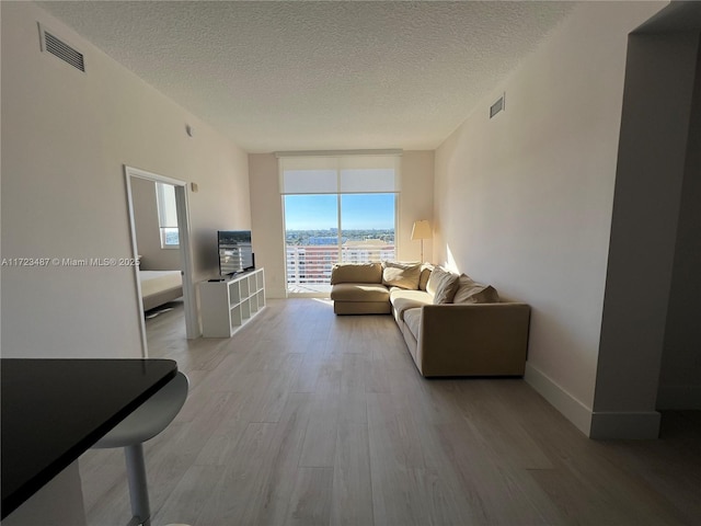 living room featuring floor to ceiling windows, a textured ceiling, and light hardwood / wood-style flooring