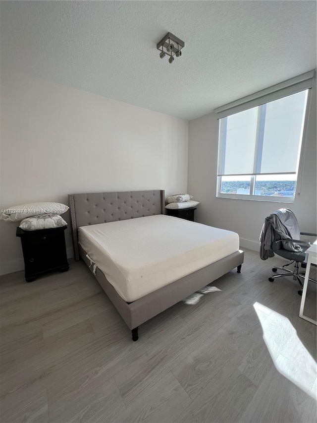 bedroom featuring light hardwood / wood-style flooring and a textured ceiling