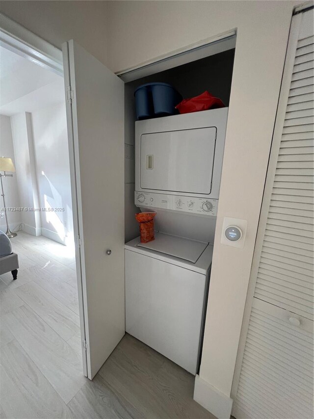 washroom with light wood-type flooring and stacked washer and dryer