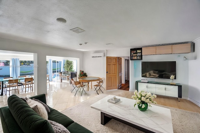 living room featuring light wood-type flooring, a textured ceiling, and a wall mounted AC