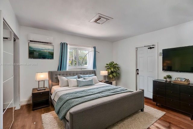 bedroom with a wall mounted air conditioner and dark wood-type flooring