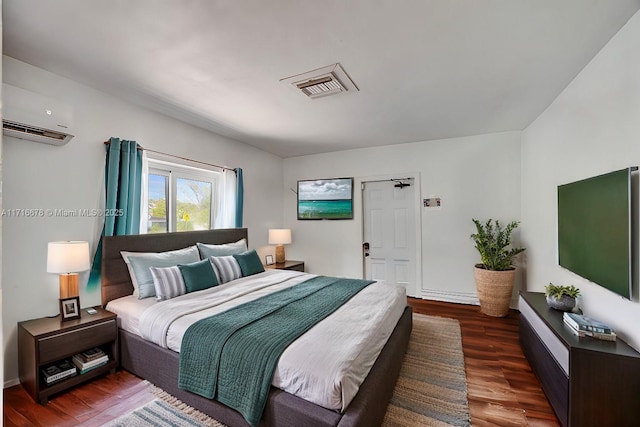 bedroom with dark hardwood / wood-style flooring and a wall unit AC