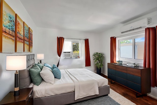 bedroom with cooling unit, dark hardwood / wood-style flooring, an AC wall unit, and multiple windows