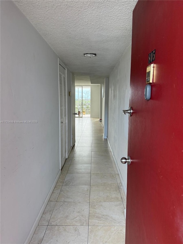 hall with light tile patterned floors and a textured ceiling