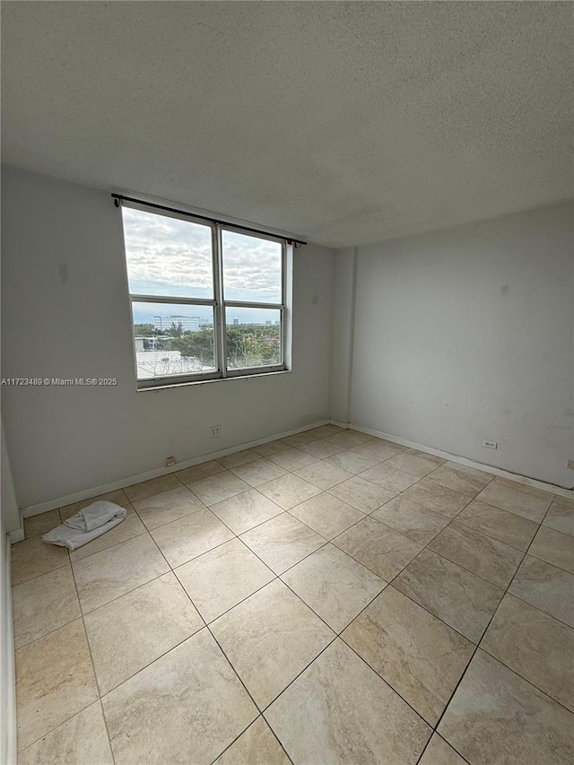 tiled empty room with a textured ceiling