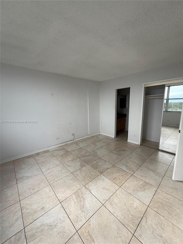 unfurnished bedroom with light tile patterned flooring, a textured ceiling, and a closet