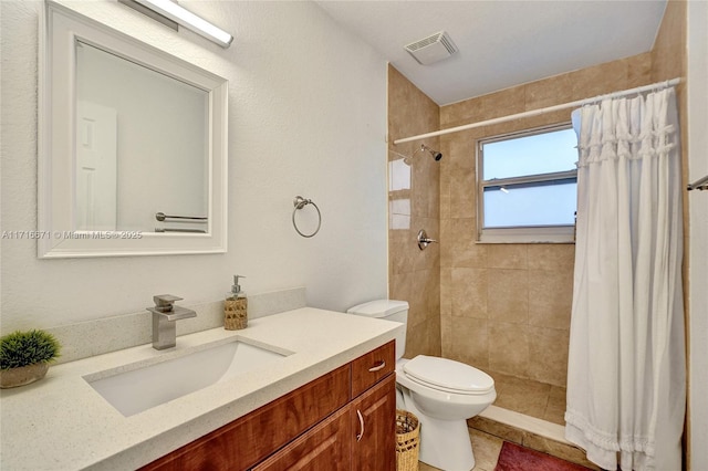 bathroom featuring vanity, toilet, visible vents, and a tile shower