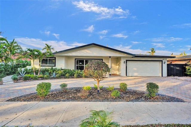 single story home with stucco siding, decorative driveway, a garage, and fence