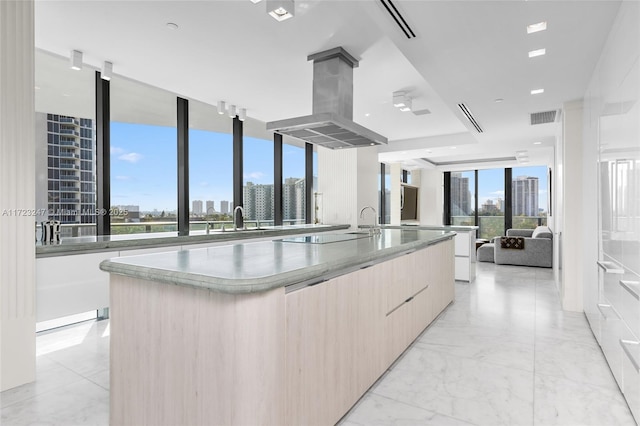 kitchen with island exhaust hood, black electric cooktop, a large island, and sink