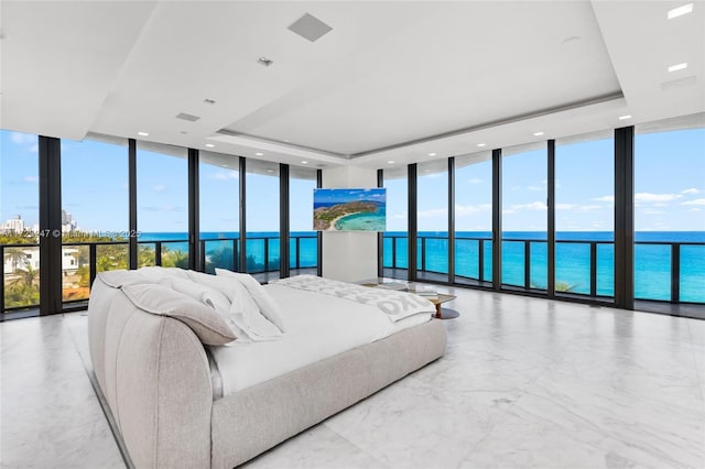 bedroom with a water view, a raised ceiling, and a wall of windows