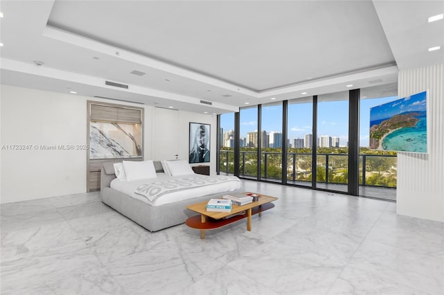 bedroom with floor to ceiling windows, a raised ceiling, and multiple windows