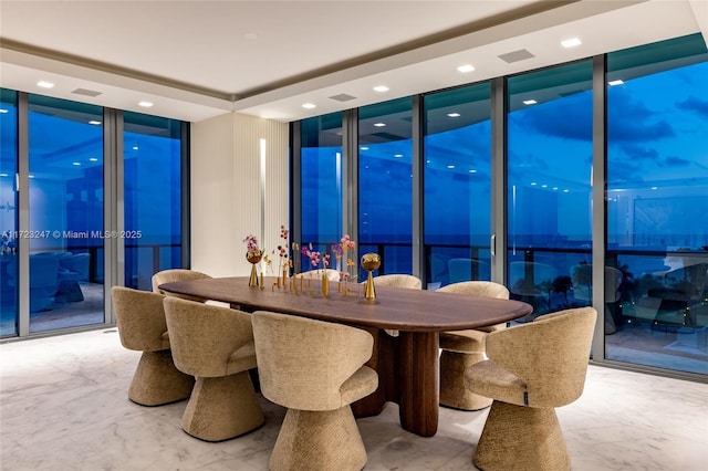 dining space with a wall of windows and a tray ceiling