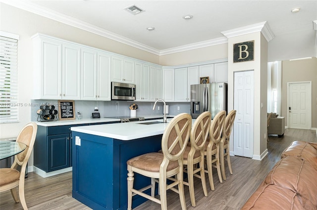 kitchen with sink, blue cabinetry, light hardwood / wood-style floors, white cabinets, and a center island with sink