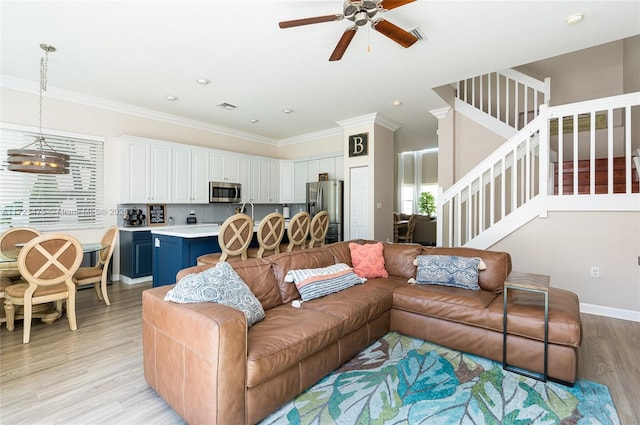 living room featuring ceiling fan, ornamental molding, and light hardwood / wood-style floors