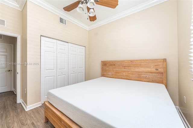 bedroom featuring ornamental molding, hardwood / wood-style floors, ceiling fan, and a closet