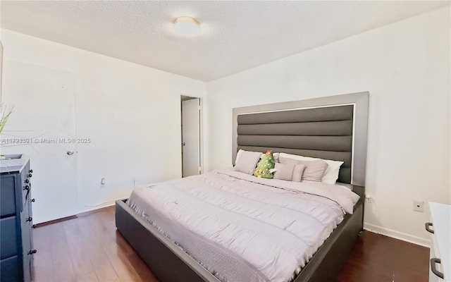 bedroom featuring a textured ceiling and dark hardwood / wood-style floors