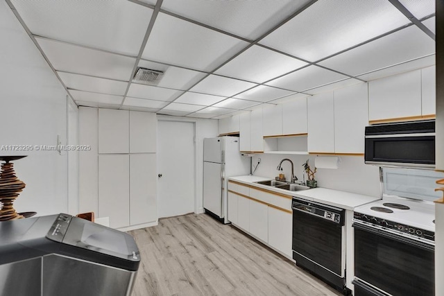 kitchen featuring a paneled ceiling, black appliances, white cabinets, sink, and light hardwood / wood-style floors