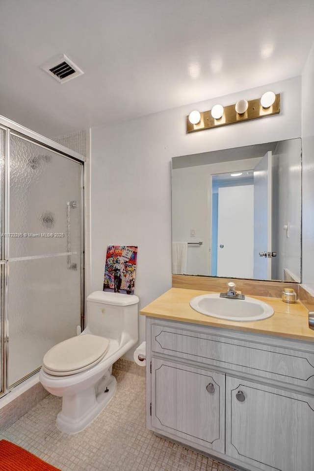 bathroom with toilet, vanity, tile patterned floors, and an enclosed shower