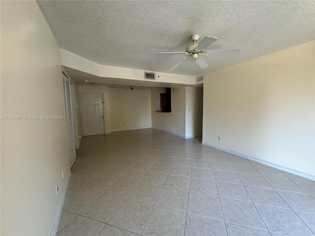 unfurnished room with ceiling fan, light tile patterned floors, and a textured ceiling