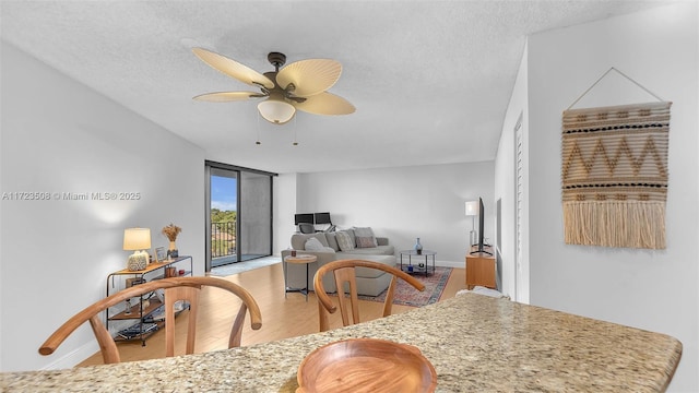 kitchen with baseboards, floor to ceiling windows, wood finished floors, a textured ceiling, and a ceiling fan