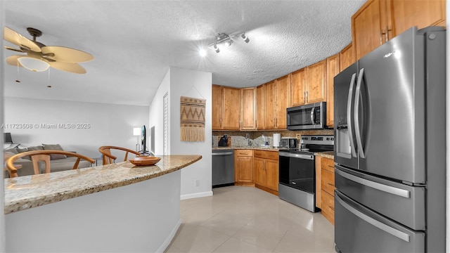 kitchen with decorative backsplash, light stone counters, light tile patterned floors, and stainless steel appliances