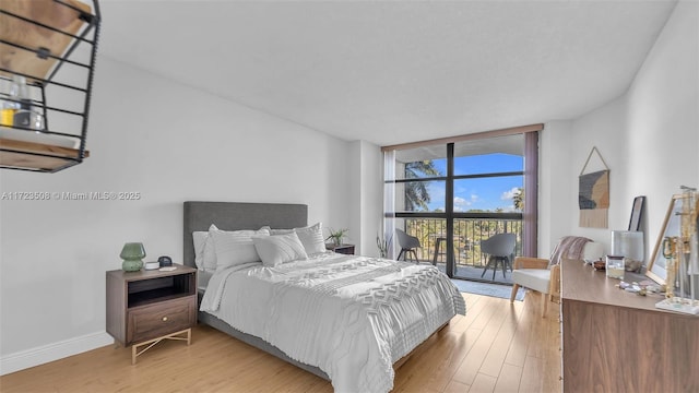 bedroom featuring access to exterior, a wall of windows, and light wood-type flooring