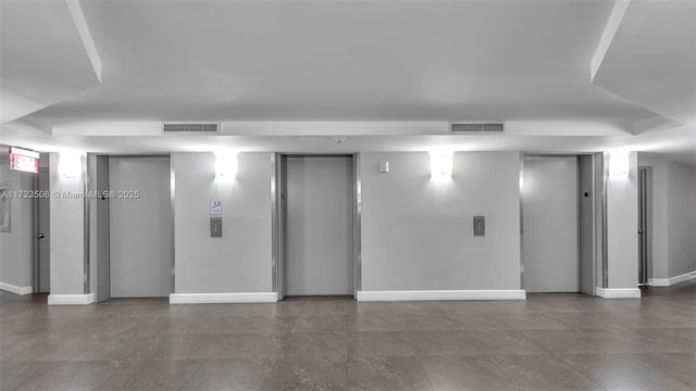 unfurnished room featuring elevator, baseboards, and visible vents