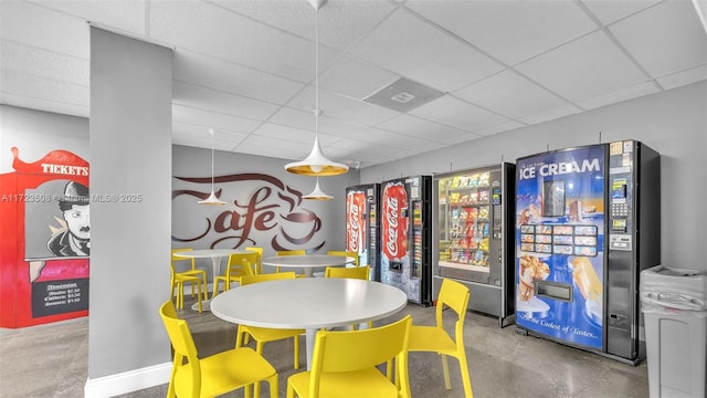 rec room with beverage cooler, a paneled ceiling, and concrete flooring