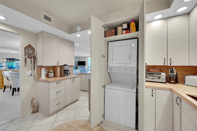 laundry area with light tile patterned flooring and stacked washer and dryer