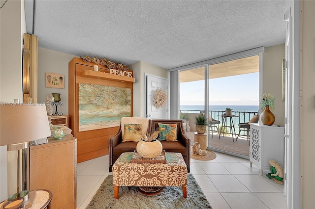 living area featuring light tile patterned floors, a textured ceiling, a water view, and floor to ceiling windows