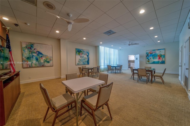 dining space with ceiling fan and light colored carpet