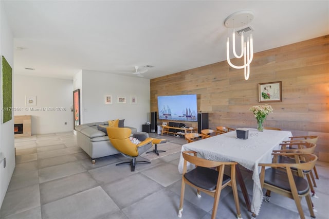 dining room with a lit fireplace and wooden walls