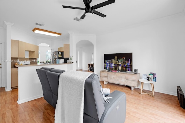 living room featuring ceiling fan, ornamental molding, and light hardwood / wood-style flooring