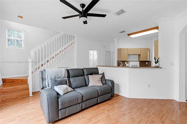 living room with ceiling fan, sink, and light hardwood / wood-style flooring