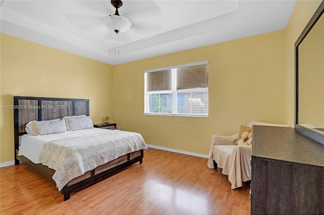 bedroom with a raised ceiling, ceiling fan, and hardwood / wood-style floors