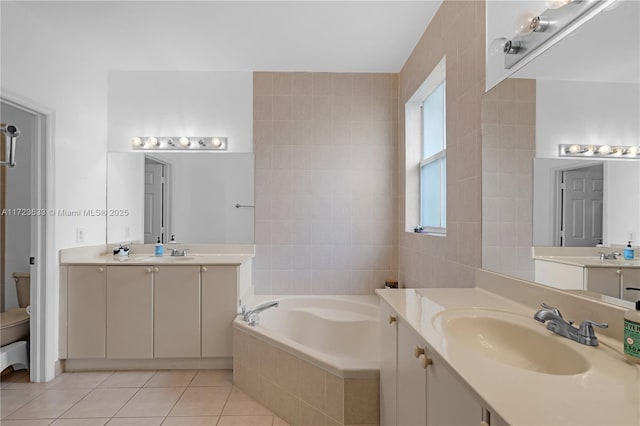 bathroom featuring toilet, vanity, tile patterned floors, and tiled tub