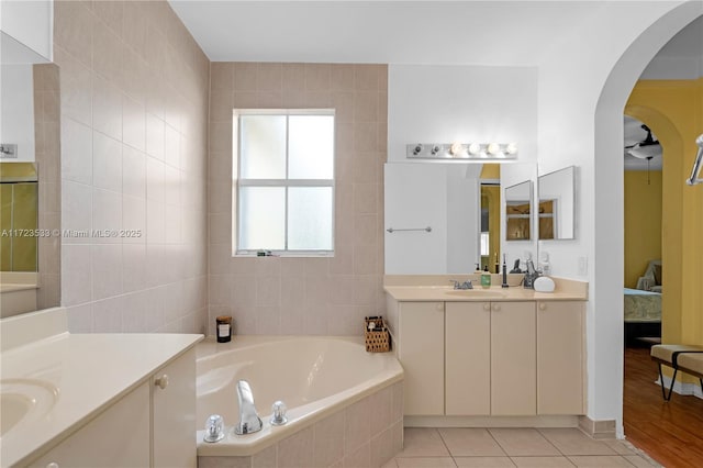 bathroom featuring tile patterned floors, vanity, and a relaxing tiled tub