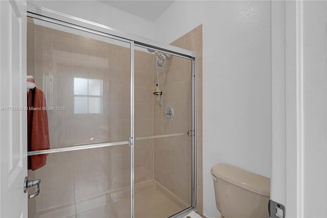 bathroom with toilet and a shower with shower door