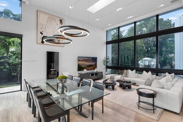 living room featuring a wall of windows, plenty of natural light, light hardwood / wood-style flooring, and a high ceiling